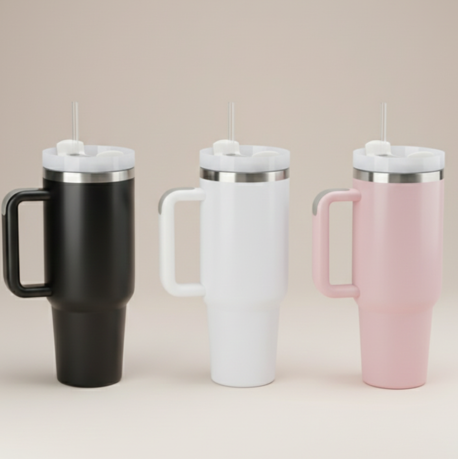 Three insulated travel mugs in black, white, and pink on a beige background